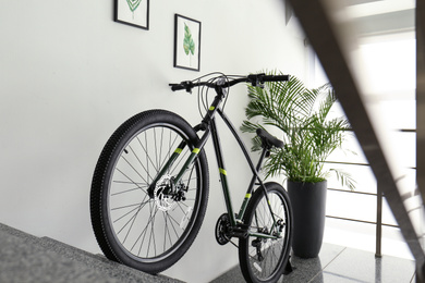 Photo of Modern black bicycle on stairs at home