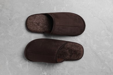 Pair of brown slippers on grey marble floor, top view