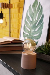 Photo of Modern night lamp, houseplants and decor on table indoors