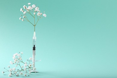 Photo of Cosmetology. Medical syringe and gypsophila flowers on turquoise background, space for text