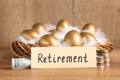 Photo of Golden eggs in nest, money and card with word Retirement on wooden table. Pension concept