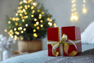 Photo of Christmas gift box on bed in festive interior