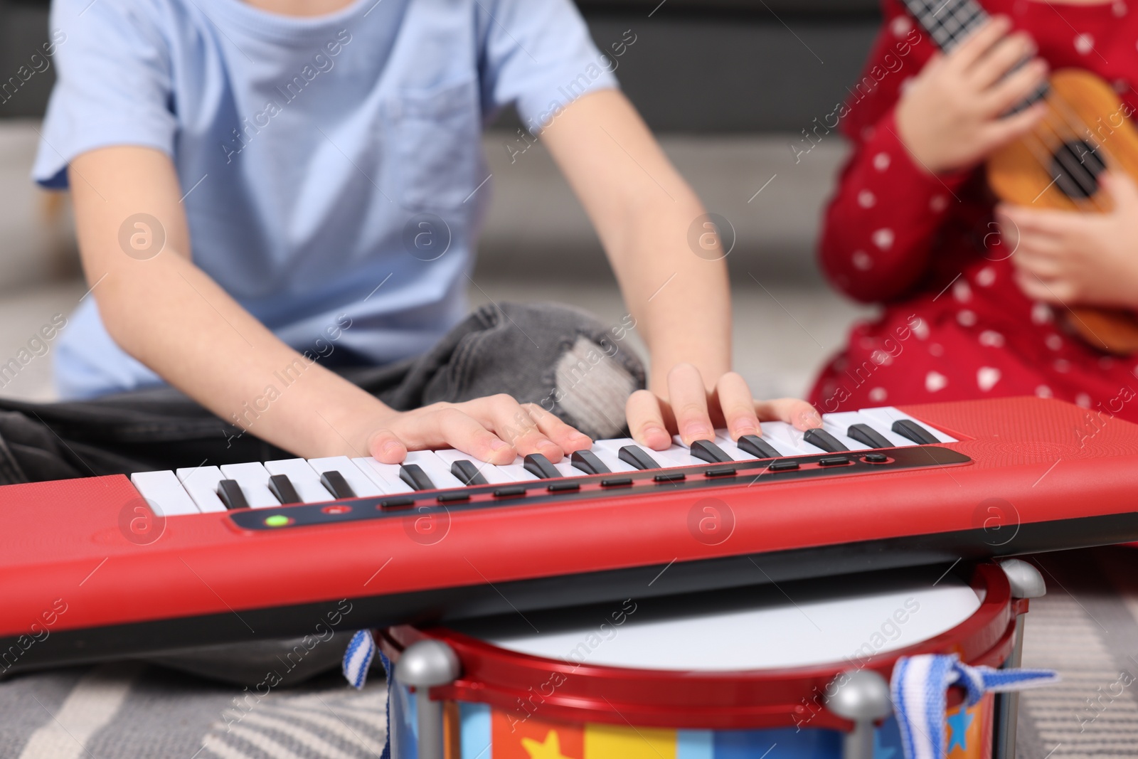 Photo of Little children playing toy musical instruments at home, closeup