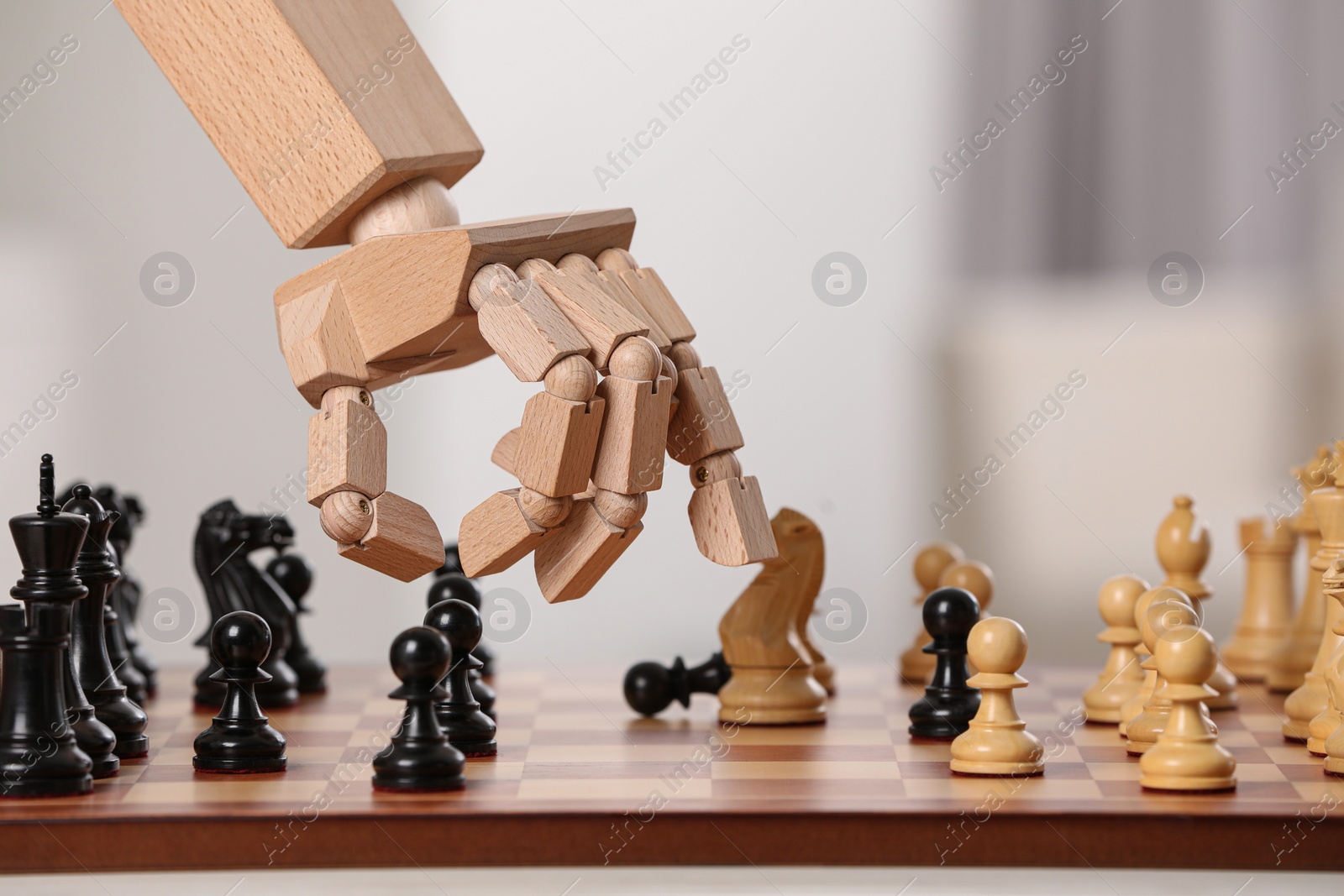 Photo of Robot moving chess piece on board against light background, closeup. Wooden hand representing artificial intelligence