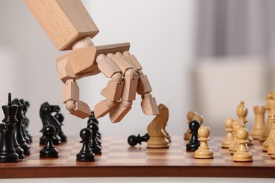 Robot moving chess piece on board against light background, closeup. Wooden hand representing artificial intelligence