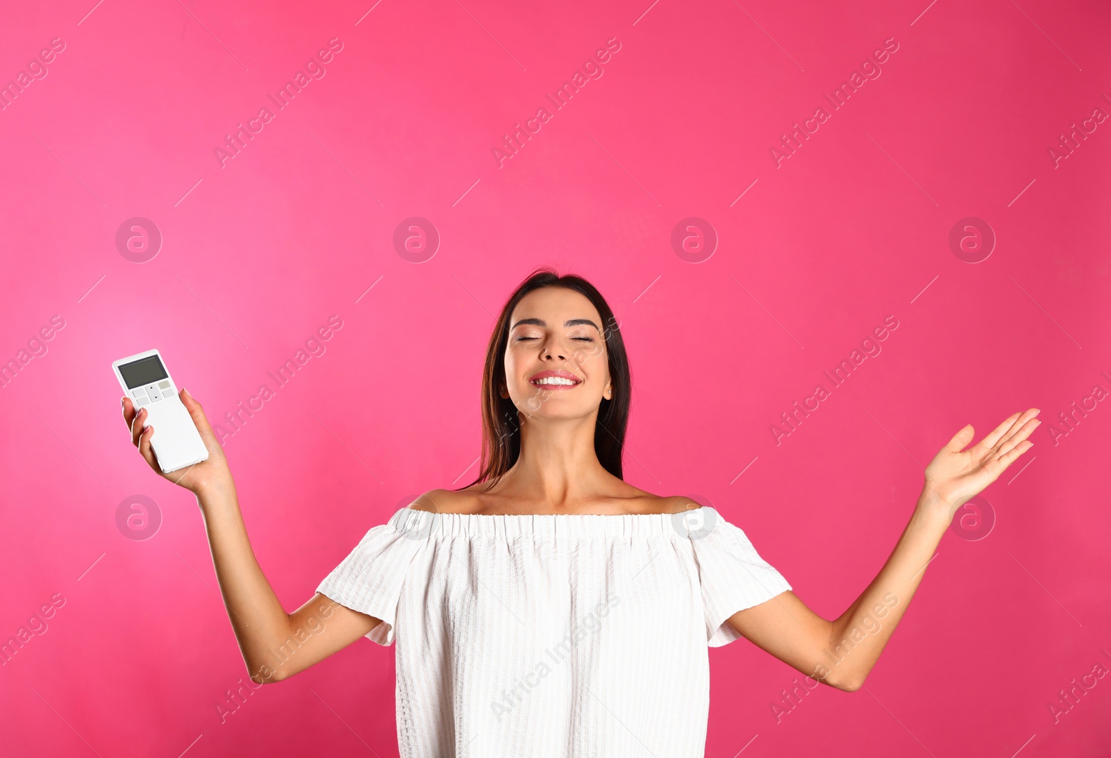 Photo of Young woman with air conditioner remote on pink background