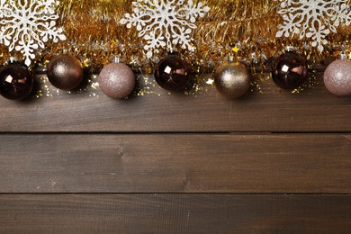 Bright tinsel and Christmas decor on wooden background, flat lay. Space for text