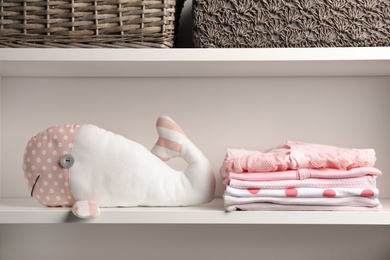 Photo of Stacked baby clothes and plush toy on shelf