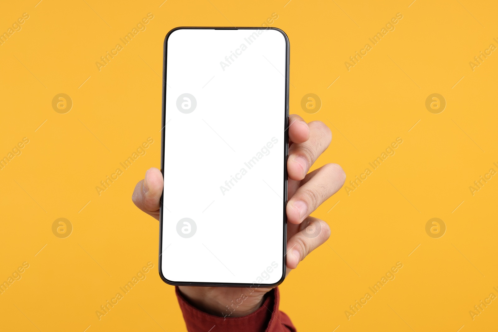 Photo of Man holding smartphone with blank screen on yellow background, closeup