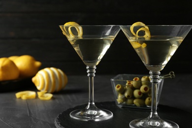 Photo of Glasses of Lemon Drop Martini cocktail with zest on grey table