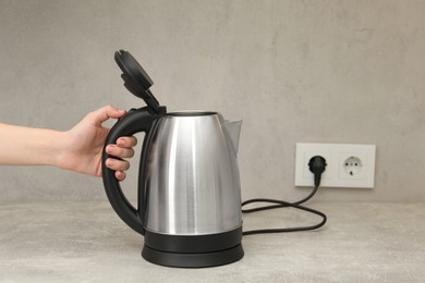 Photo of Woman with electric kettle in kitchen, closeup