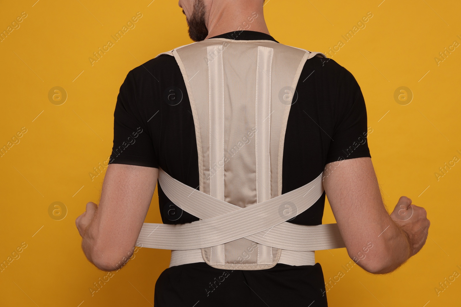 Photo of Closeup of man with orthopedic corset on orange background, back view