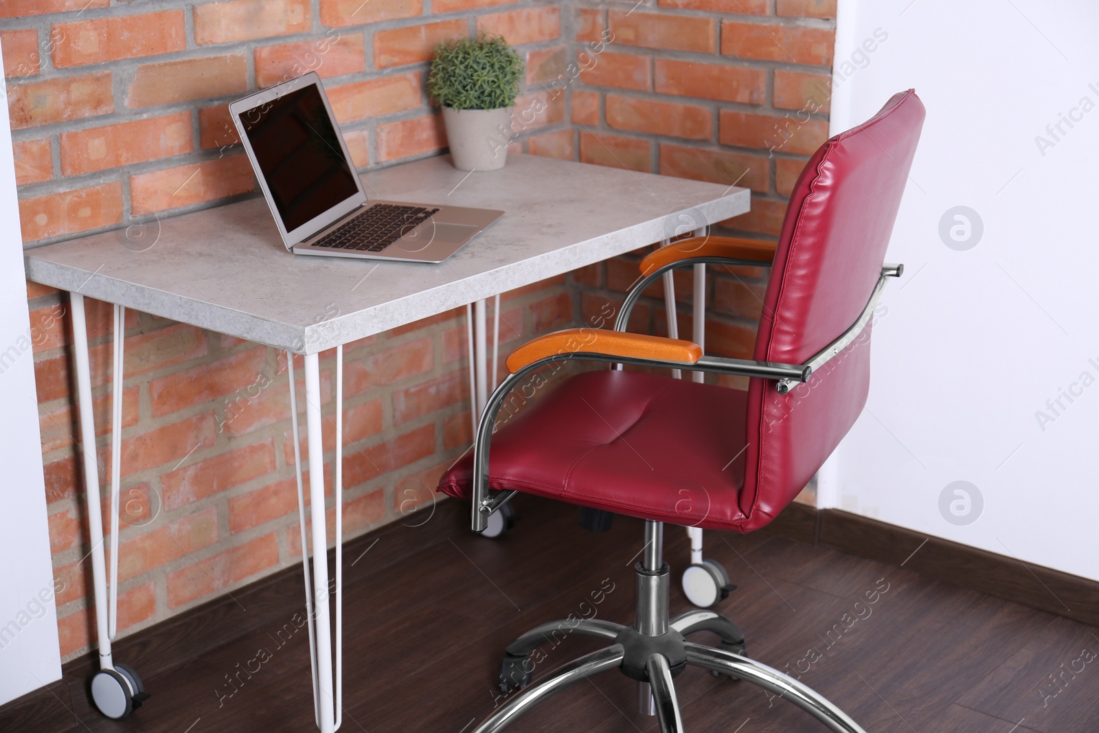 Photo of Comfortable red desk chair near table with laptop in modern office