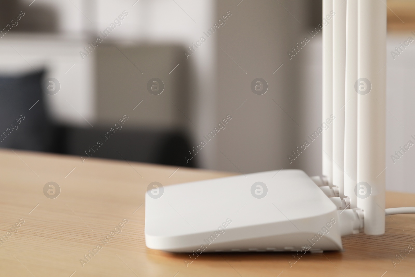 Photo of New white Wi-Fi router on wooden table indoors. Space for text