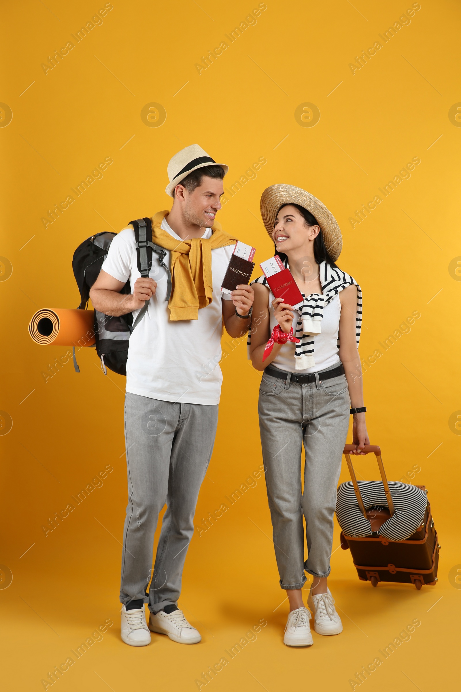 Photo of Couple of tourists with tickets, passports and luggage on yellow background