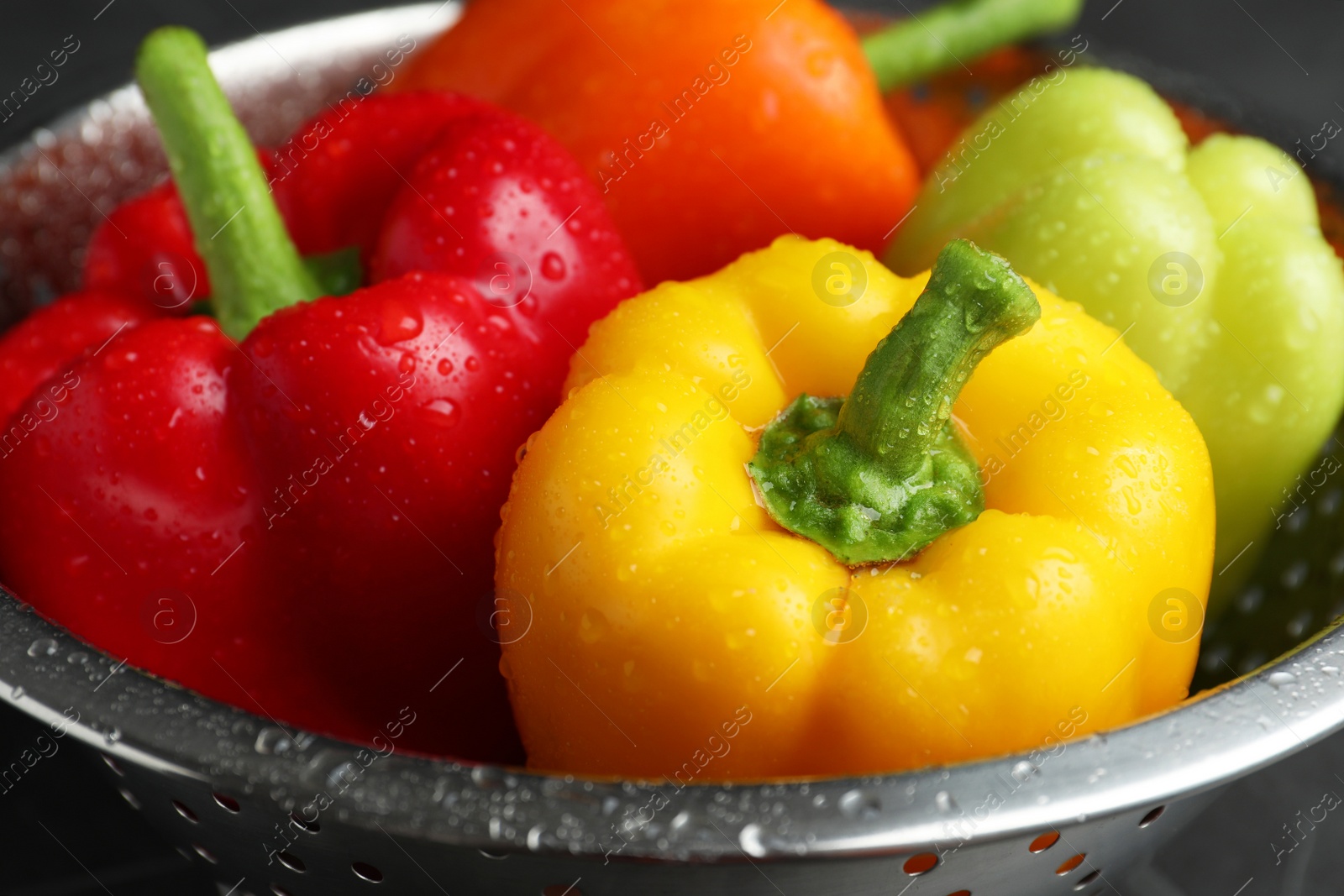 Photo of Colander with wet ripe bell peppers, closeup