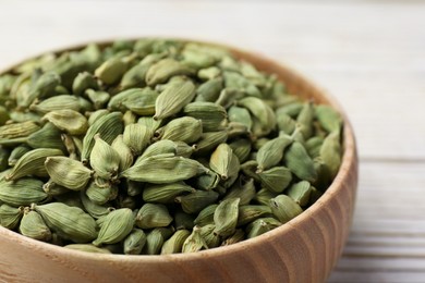 Photo of Bowl with dry cardamom on wooden table, closeup