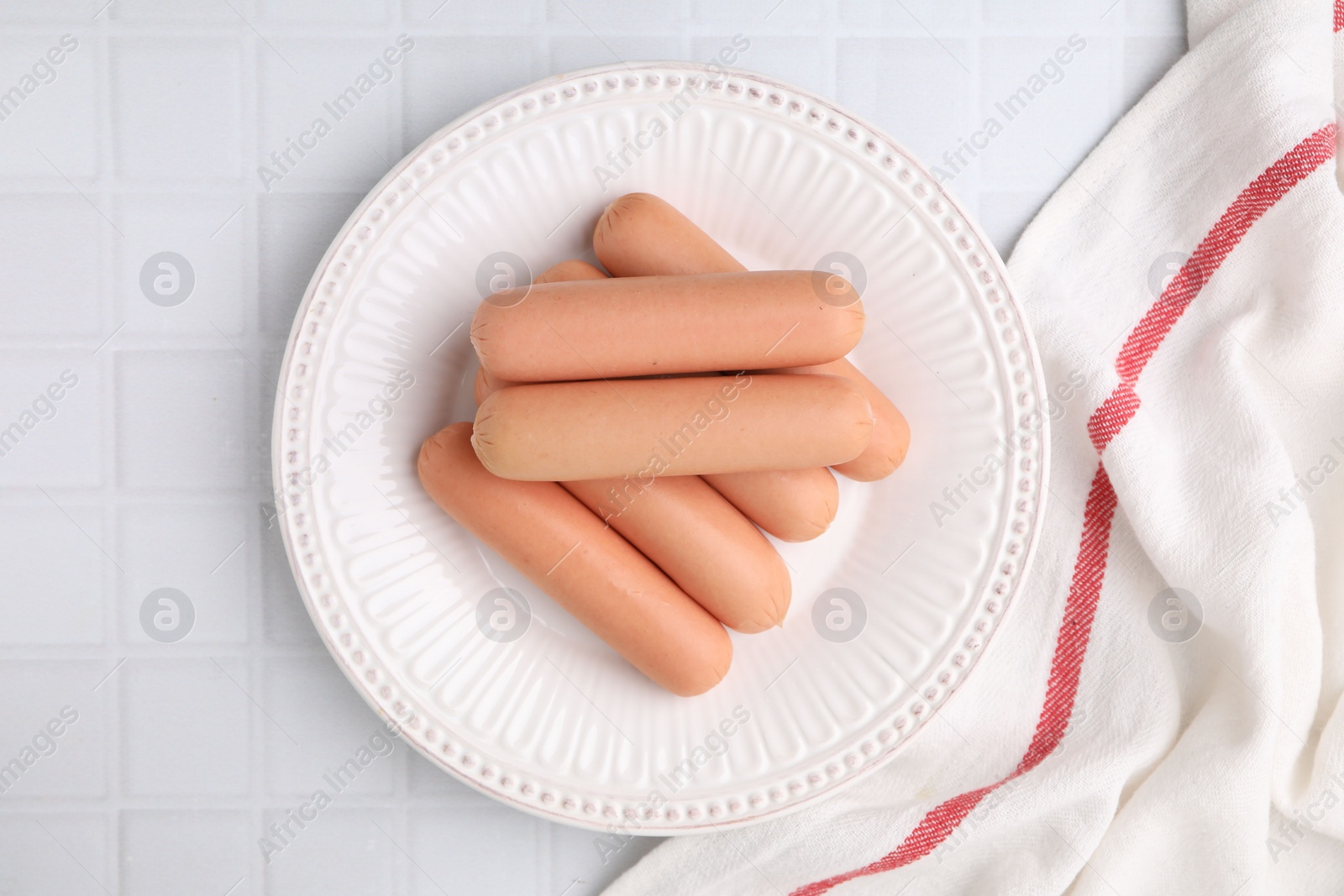 Photo of Delicious boiled sausages on white tiled table, top view