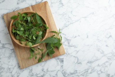 Photo of Fresh stinging nettle leaves on white marble table, top view. Space for text