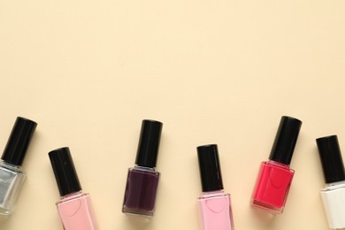 Bright nail polishes in bottles on beige background, flat lay. Space for text