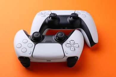 Photo of Two wireless game controllers on orange background