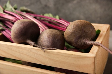 Wooden crate with fresh beets on grey background, closeup