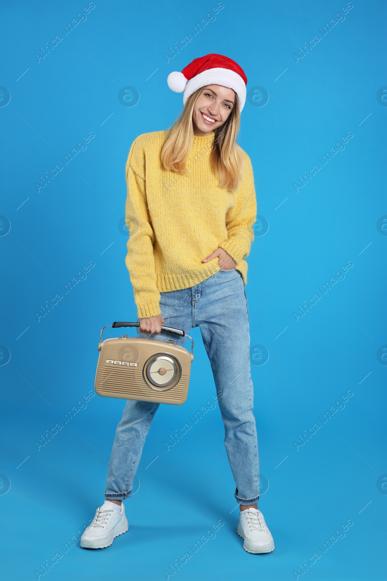 Photo of Happy woman with vintage radio on blue background. Christmas music