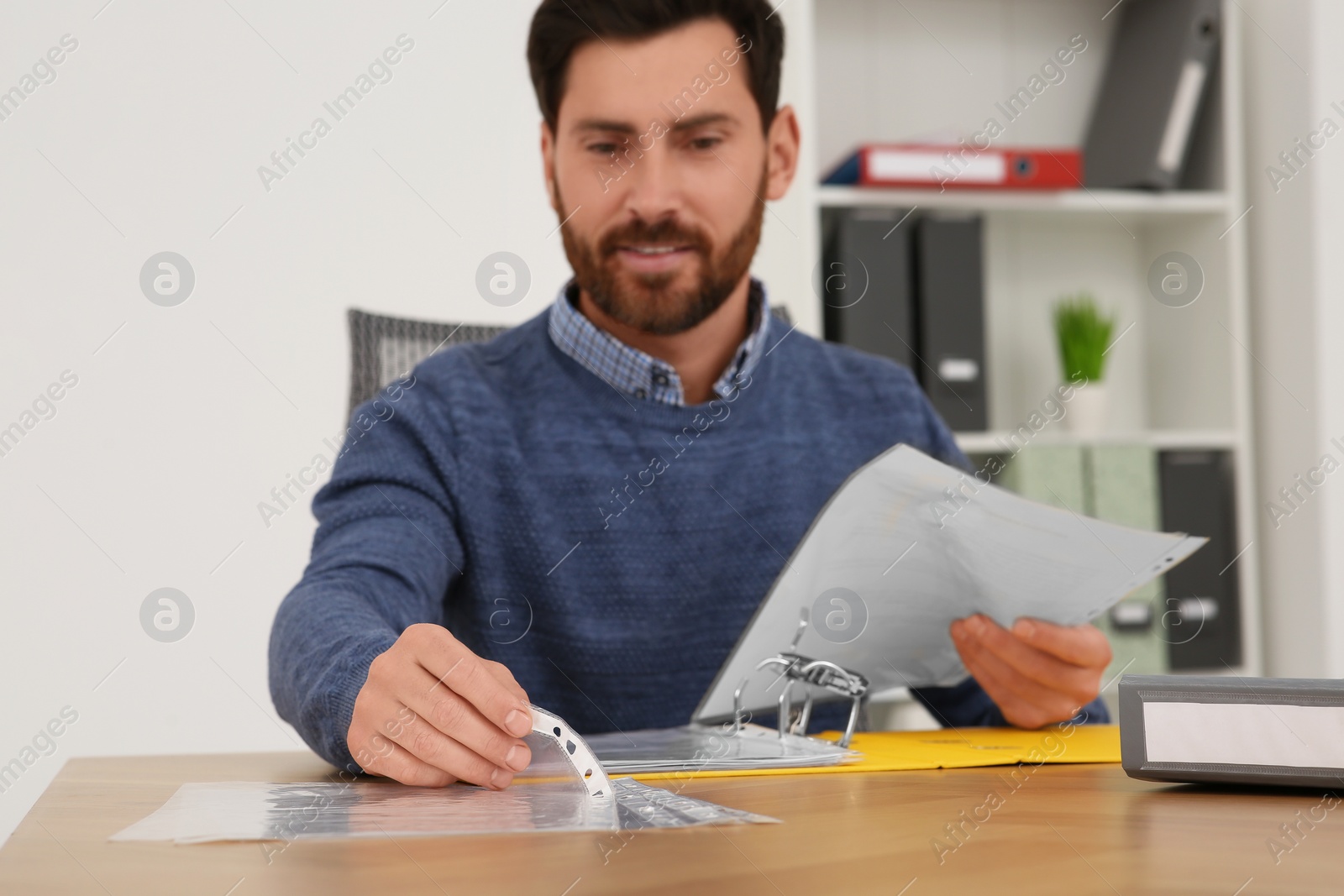 Photo of Businessman taking punched pocket on wooden table in office