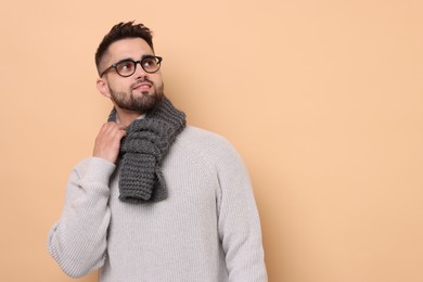 Photo of Smiling man in knitted scarf on beige background. Space for text