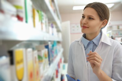 Photo of Professional pharmacist near shelves in modern drugstore