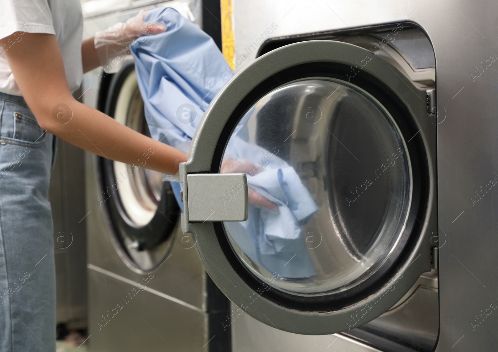 Photo of Young woman unloading washing machine in dry-cleaning, closeup