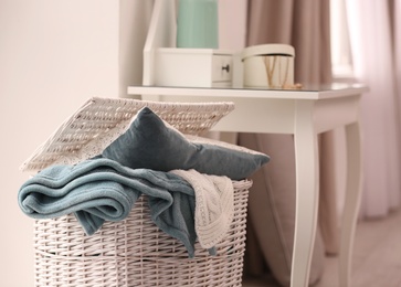 Photo of Basket with blankets and pillow near dresser indoors