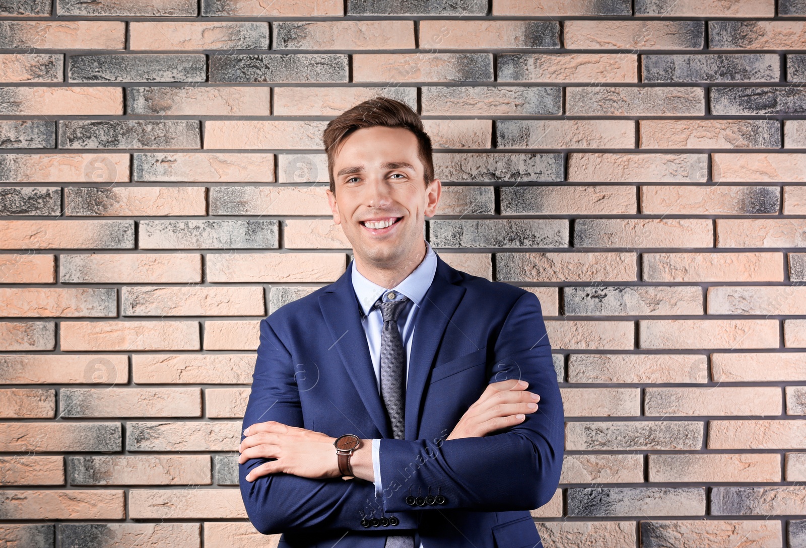 Photo of Handsome young man in suit near brick wall background