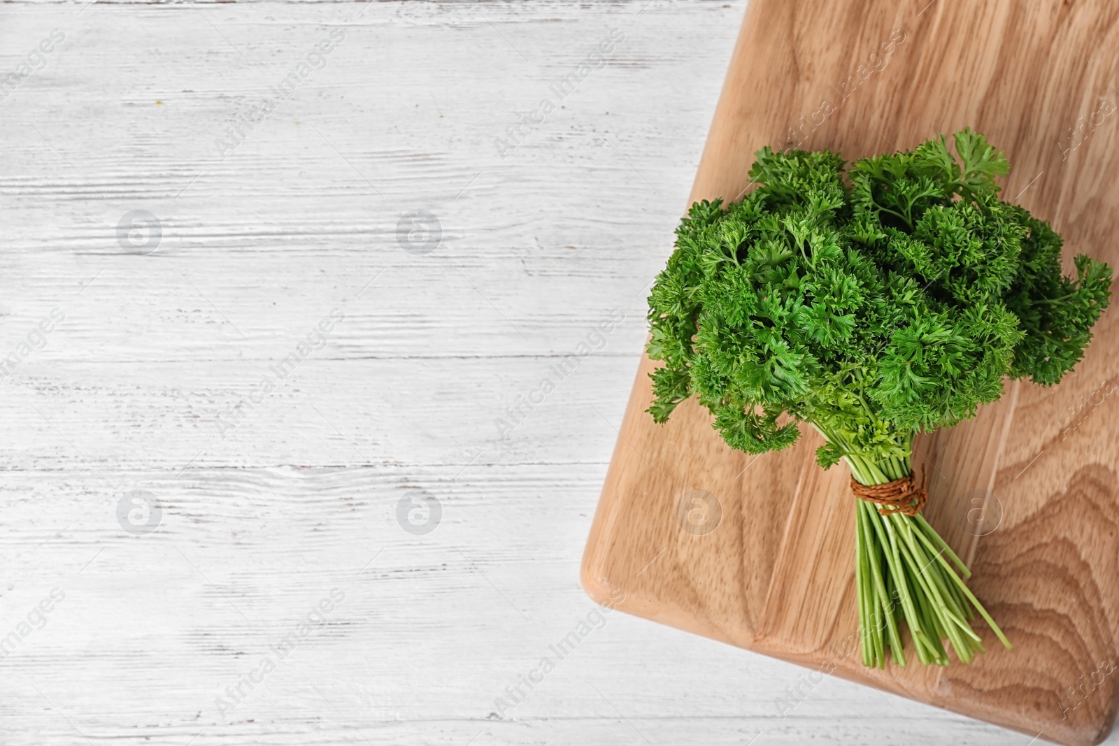 Photo of Board with fresh green parsley and space for text on wooden background, top view