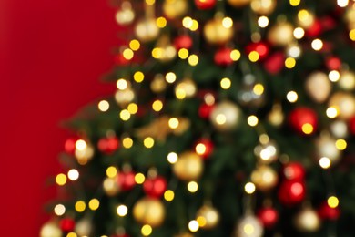 Blurred view of beautifully decorated Christmas tree  on red background, closeup