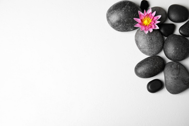 Stones with lotus flower and space for text on white background, flat lay. Zen lifestyle