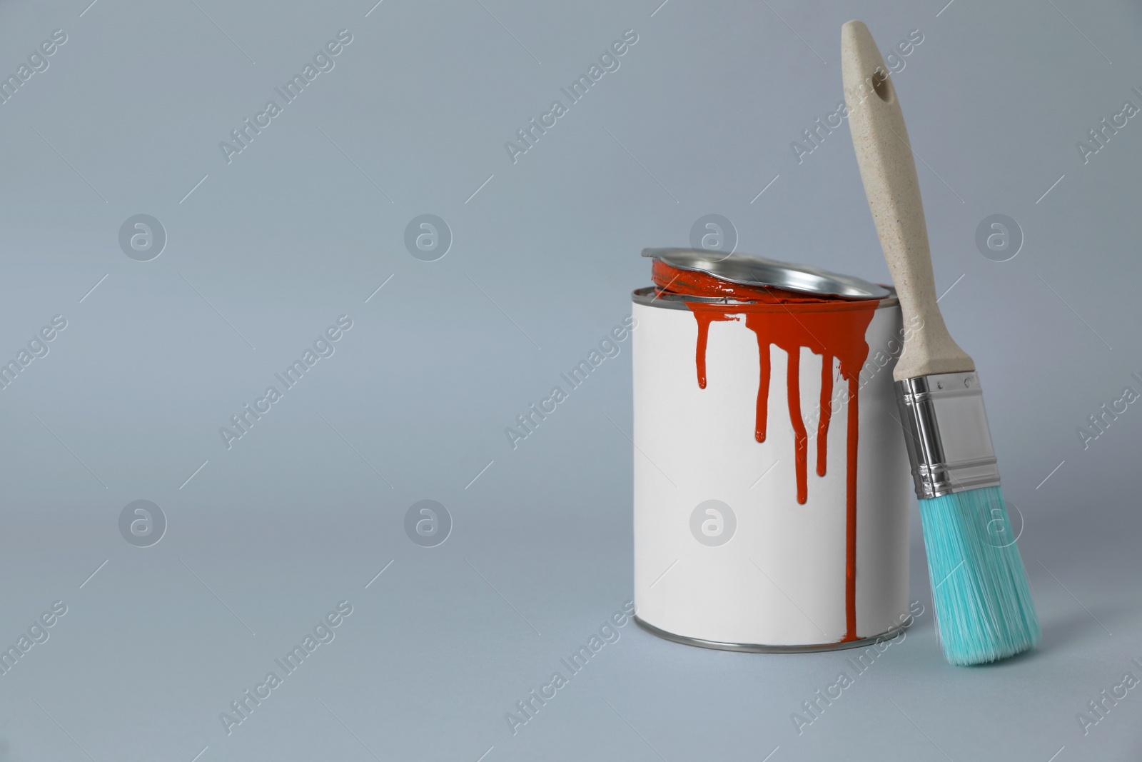 Photo of Can of orange paint and brush on grey background. Space for text