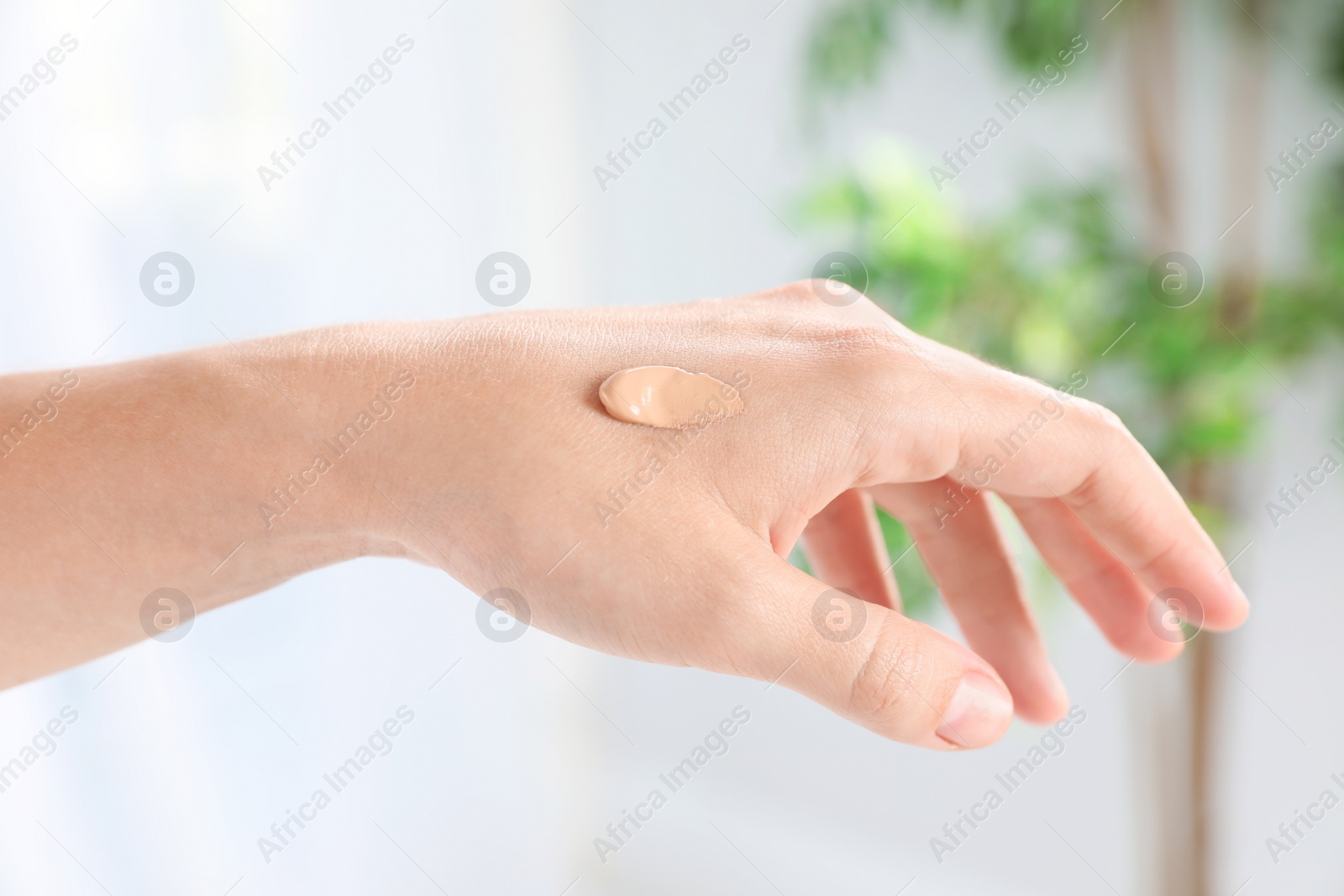 Photo of Woman testing foundation tone on hand, closeup