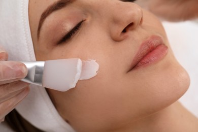 Photo of Young woman during face peeling procedure in salon, closeup