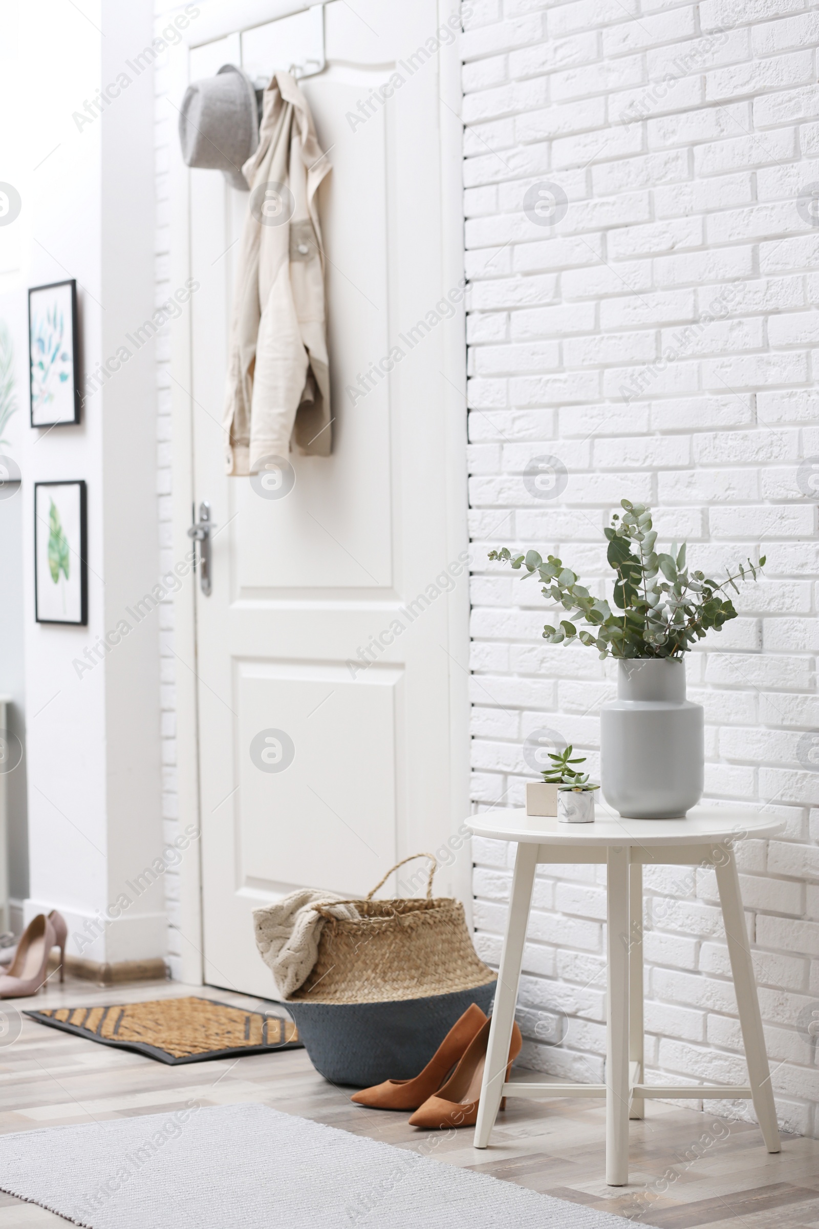 Photo of Vase with fresh eucalyptus branches on table in entryway. Interior design