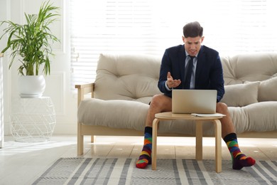 Photo of Businessman in jacket and underwear having videocall on laptop at home