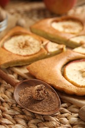 Nutmeg powder, seed and tasty apple pie on wicker mat, closeup