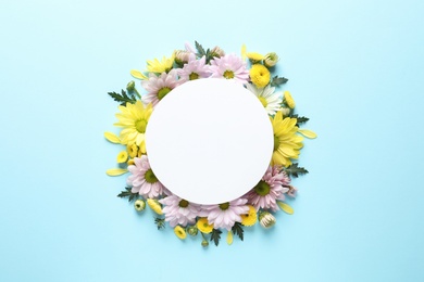 Photo of Beautiful chamomile flowers and paper card on color background, flat lay with space for text