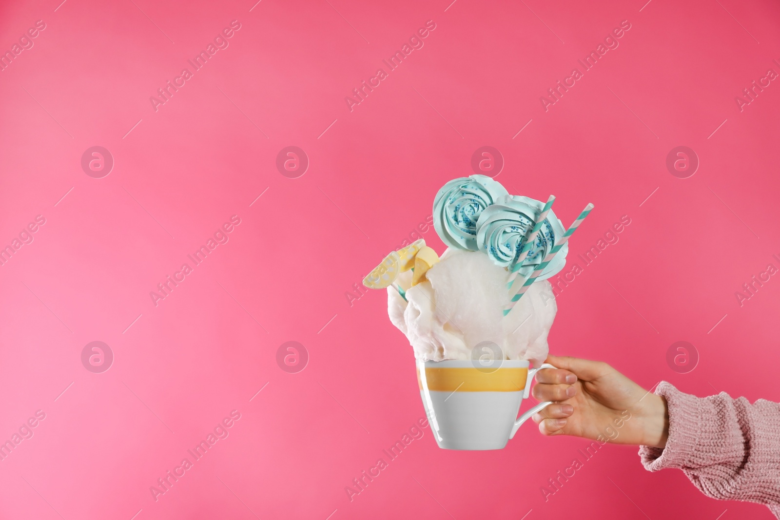 Photo of Woman holding tasty cotton candy dessert on pink background, closeup. Space for text