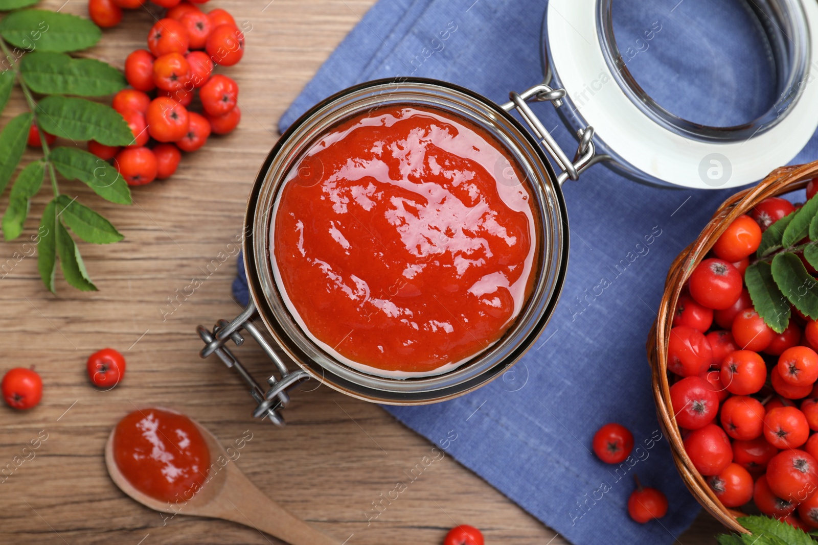 Photo of Flat lay composition with delicious rowan jam and berries on wooden table