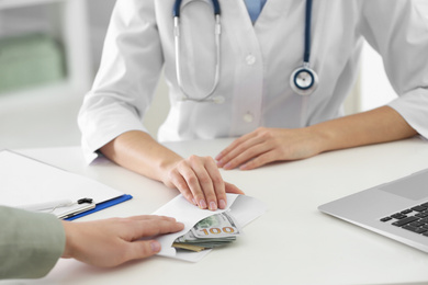 Patient giving bribe to doctor in clinic, closeup. Corrupted medicine