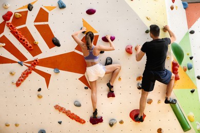Image of Athletic man and woman climbing wall in gym, back view 