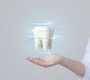 Dentist demonstrating virtual model of healthy tooth on light background, closeup