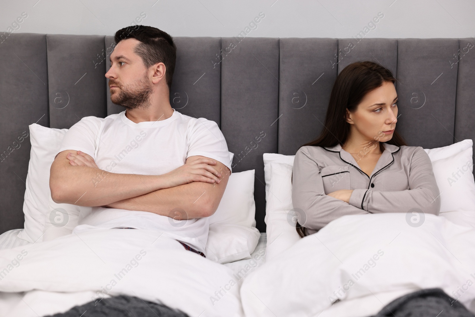 Photo of Offended couple ignoring each other after quarrel in bed. Relationship problems