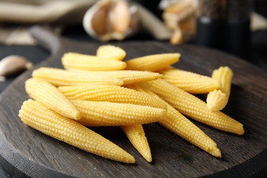 Fresh baby corn cobs on wooden board, closeup